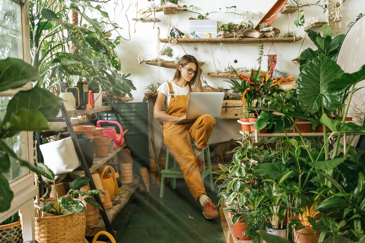 Young woman using laptop in a small gardening shop