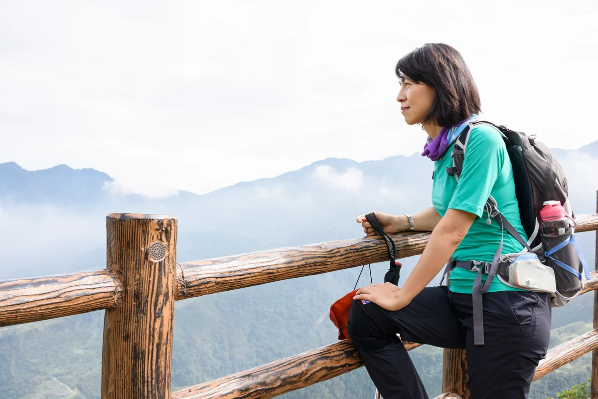 Woman leaning on fence on top of hill