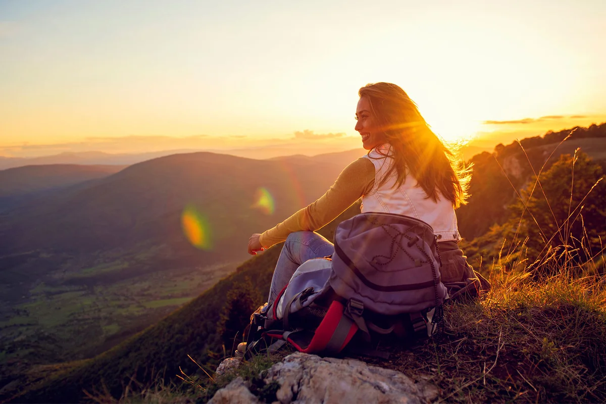 smiling woman sitting on mountain top