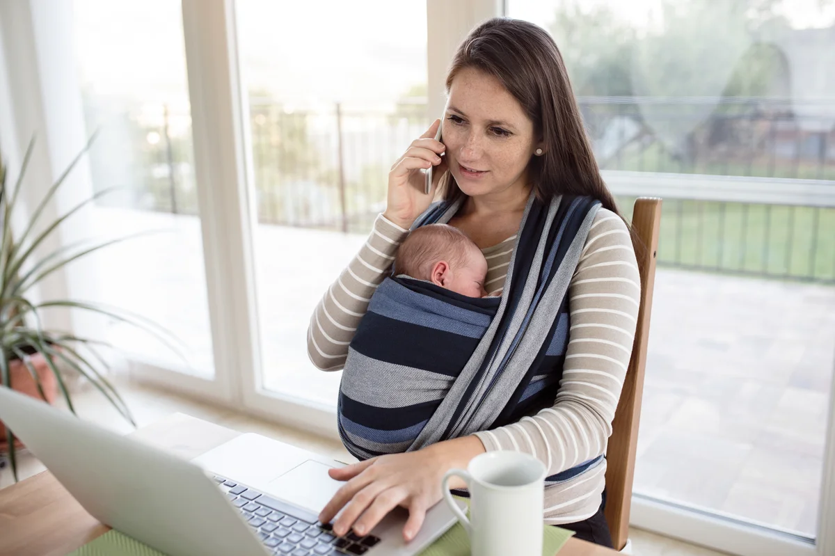 working from home mom using hands free infant carrier