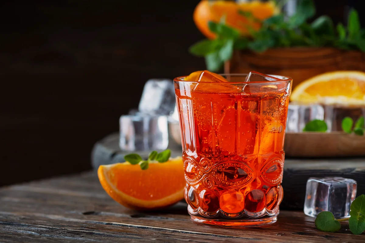 Mezcal Negroni cocktail in crystal glasses with orange slice and fresh raw oranges