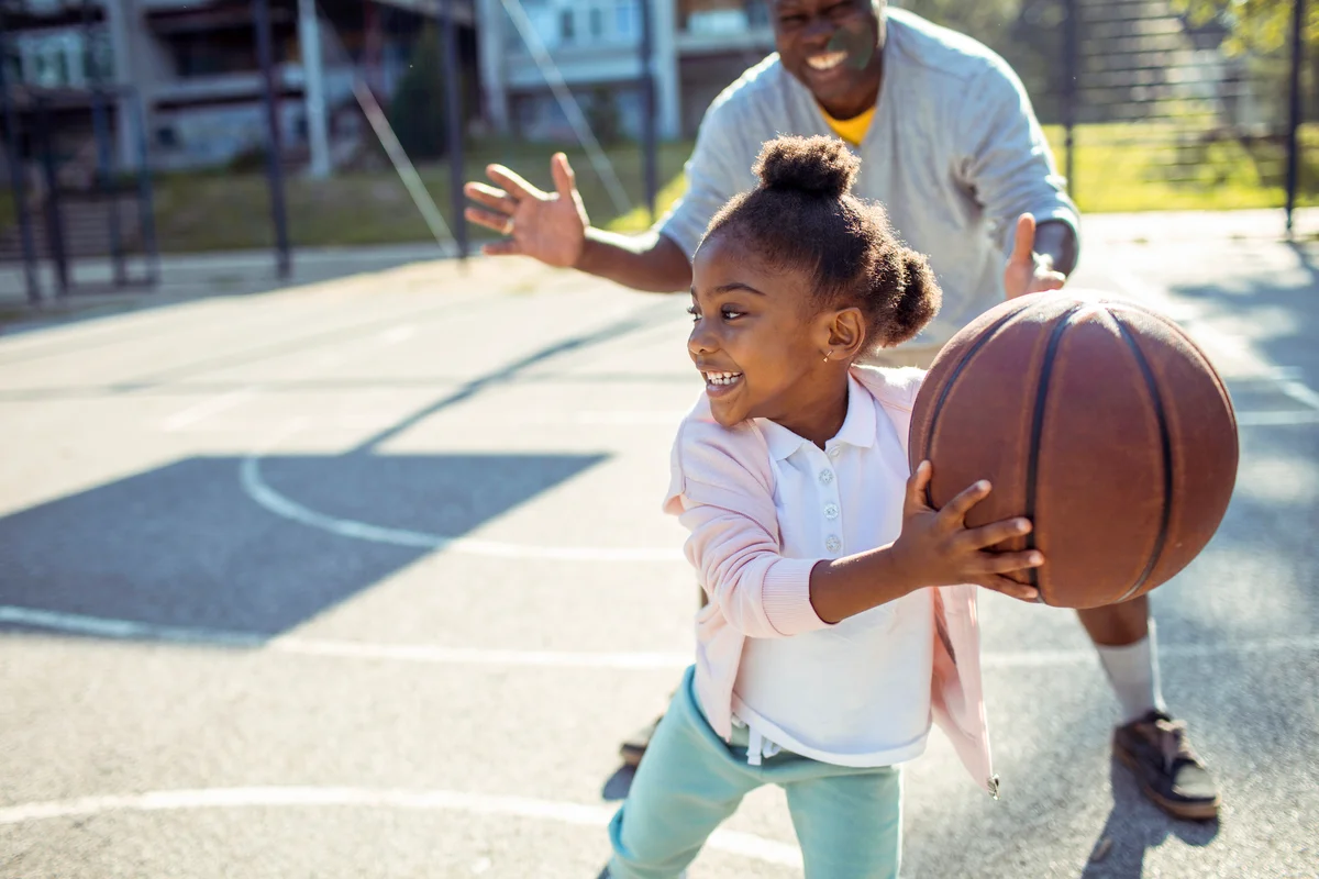 Grandfather taking his granddaughter to play some basketball in the park