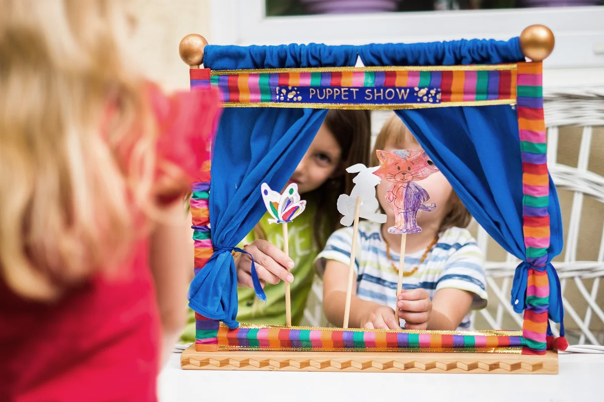 Back view girk looking puppet show that play her brother and sister