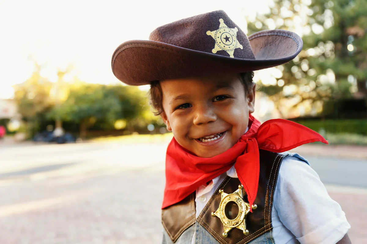Mixed race boy in cowboy costume smiling outdoors