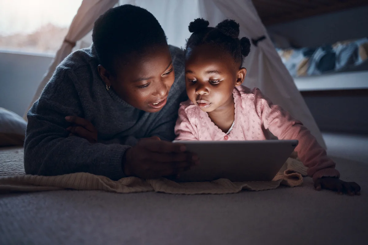 mother reading bedtime stories with her daughter on a digital tablet