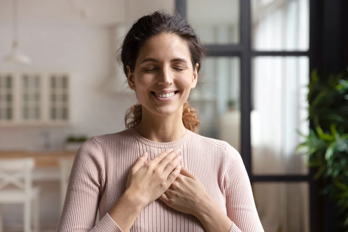 Peaceful woman with closed eyes keep hands to heart