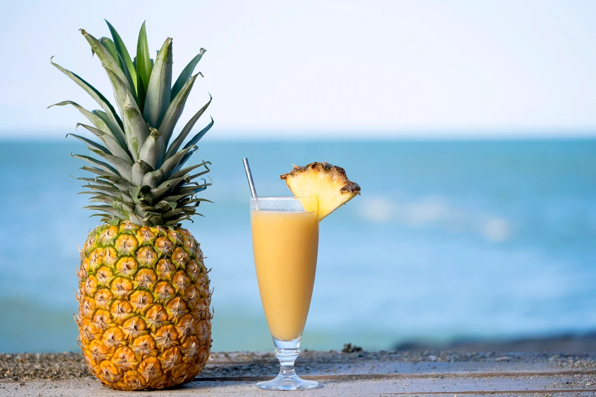 Pineapple drink in a glass glass next to the beach