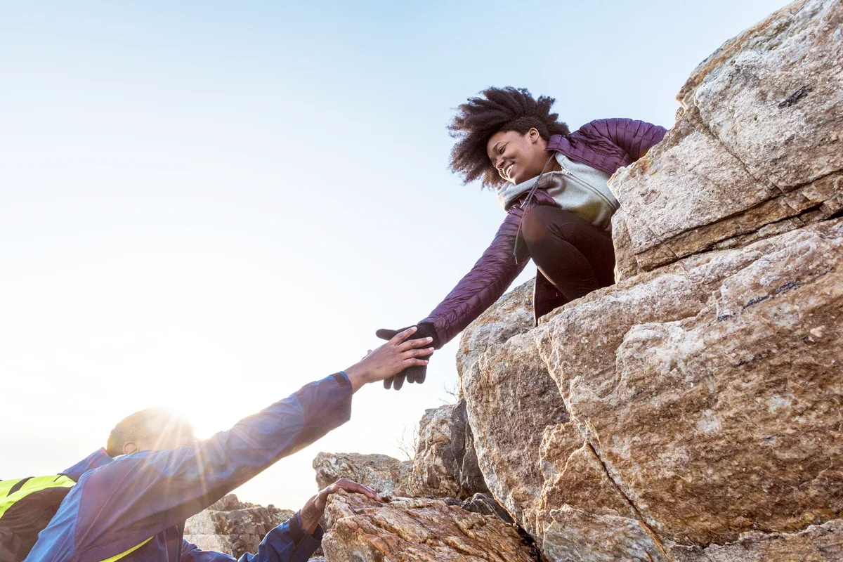 Woman helping man up rock outcrop