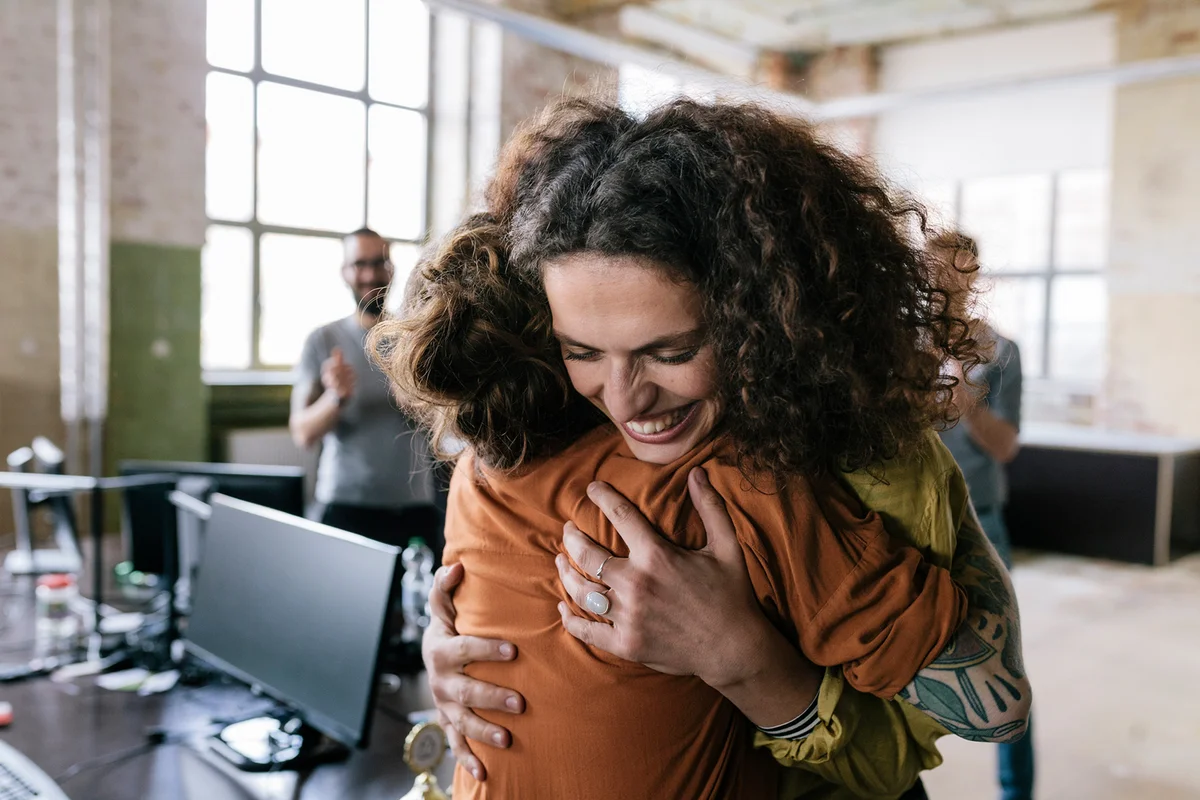 Woman is being hugged by one of her co-worker.