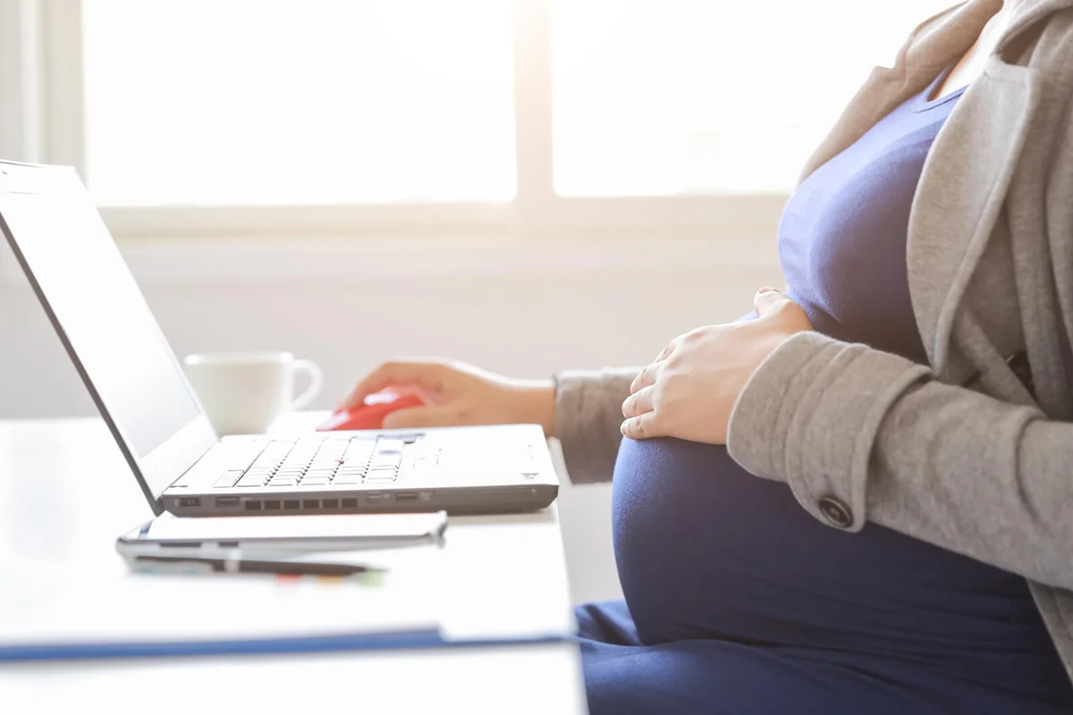 pregnant woman is working on computer laptop