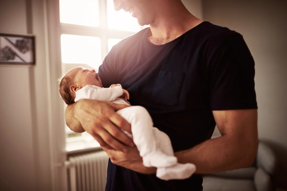 new father holding infant taking leave of absence from job