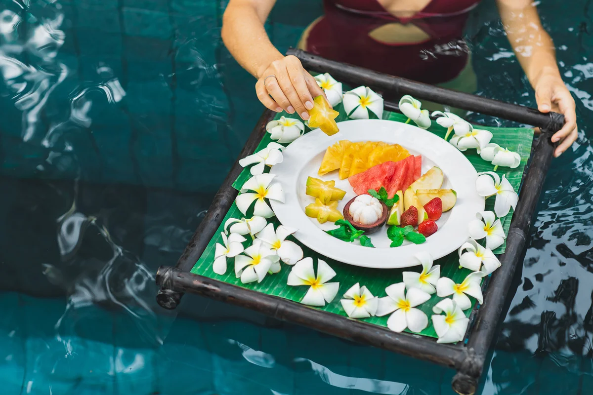 Tropical breakfast with fresh fruit on floating tray in swimming pool