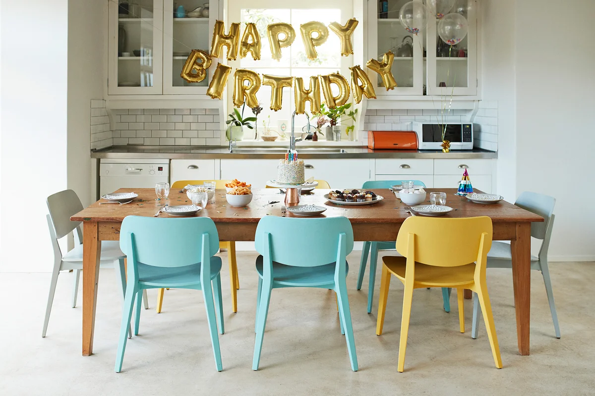 Chairs arranged around dining table in kitchen during birthday party at home