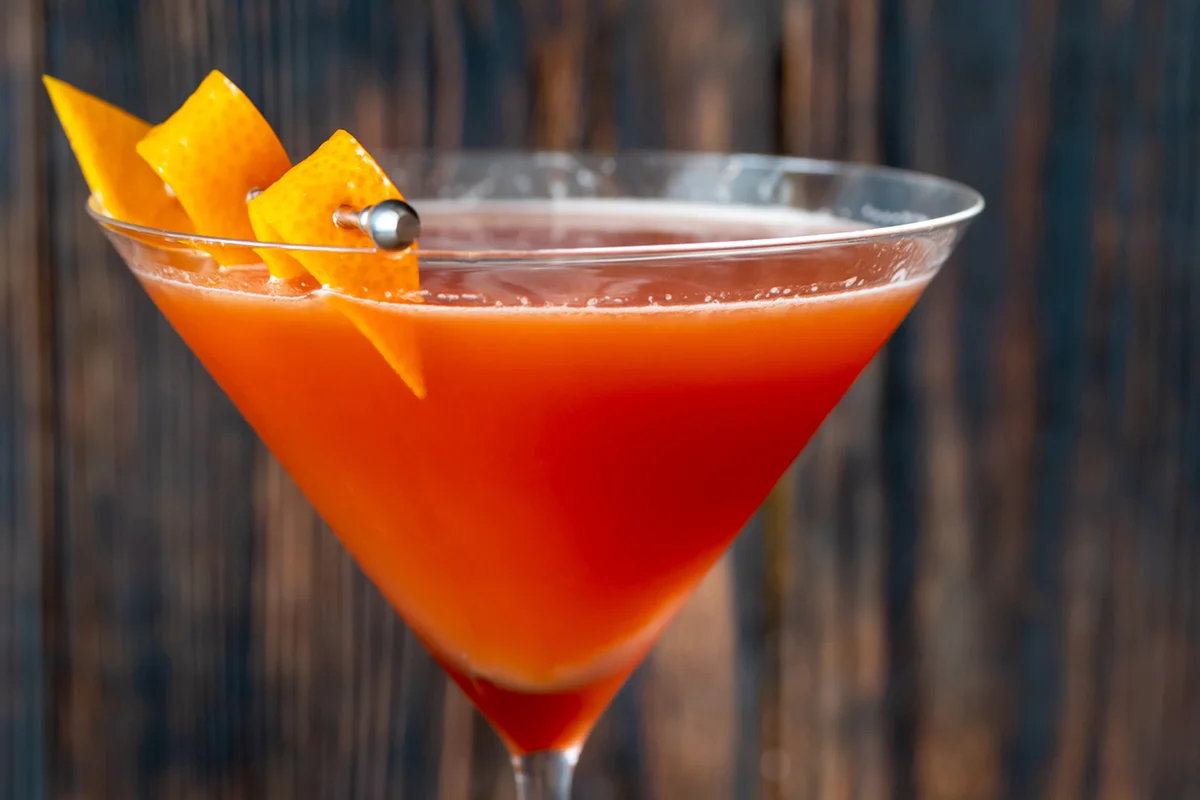 Glass of Blood And Sand Cocktail in martini glass garnished with orange peel