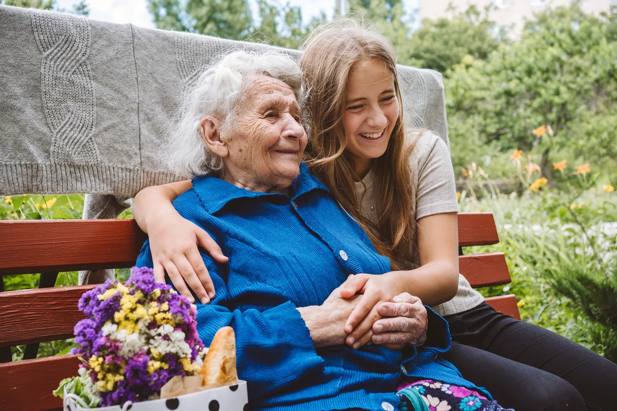 Senior Old Grandma Hugs Granddaughter Outdoors