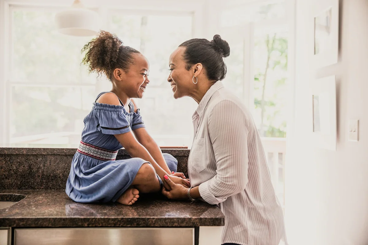 Mother and young daughter laughing in kitchen