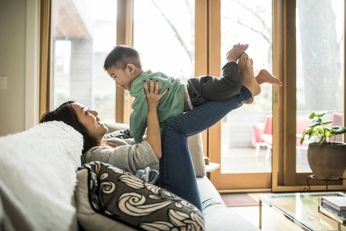 Mother playing with young son on couch at home