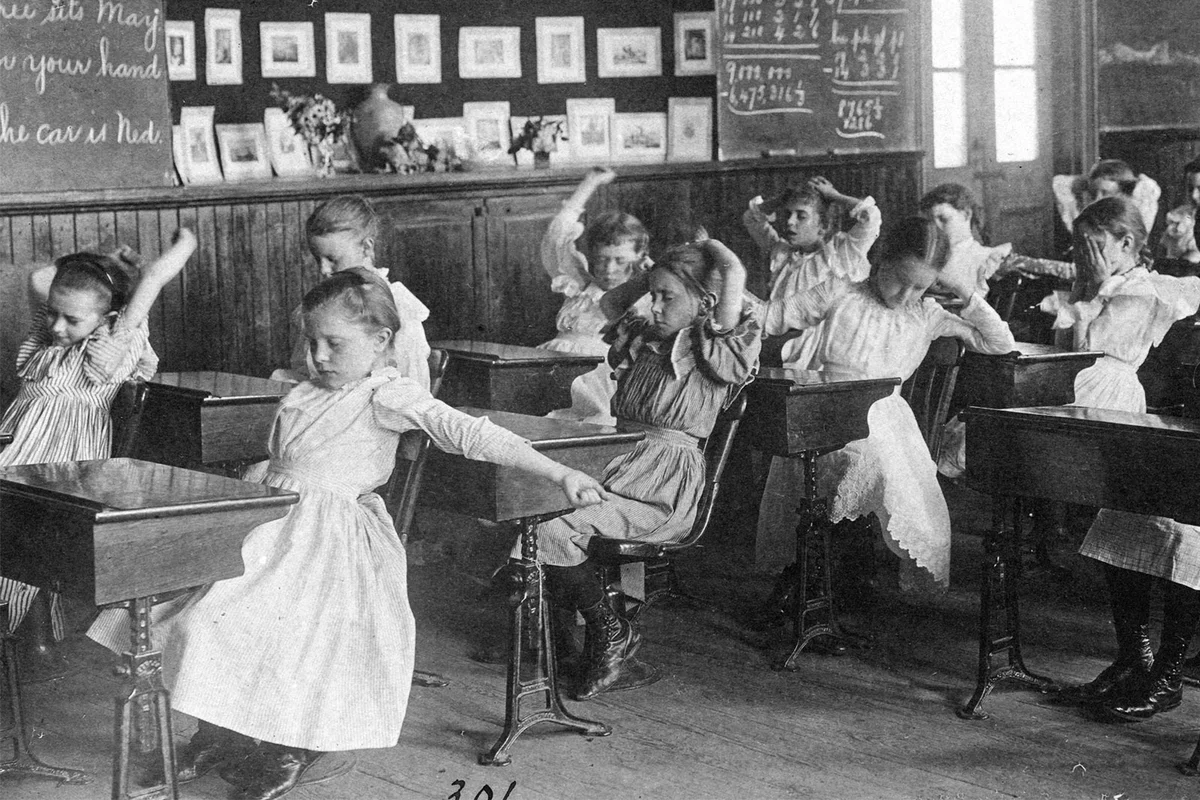 Children doing calisthenics while sitting at their desks 1899