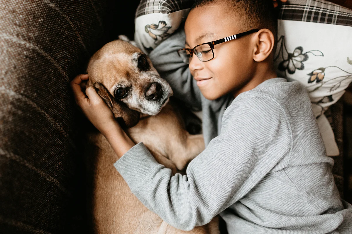 Boy cuddling with dog on couch