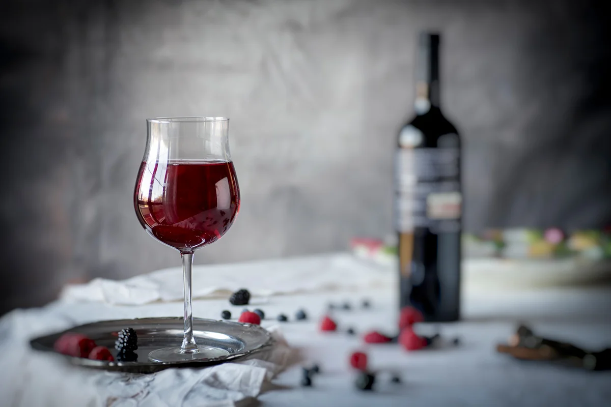 Red wine with berries on table