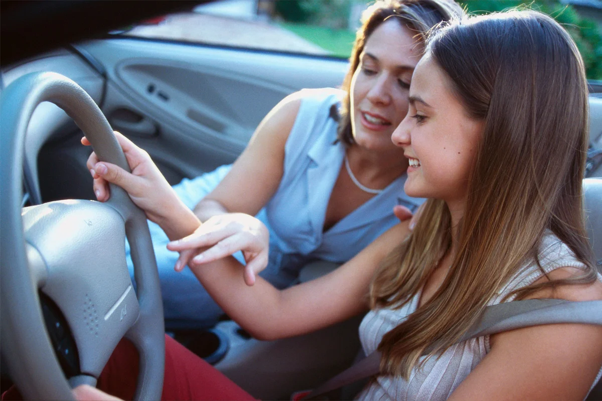 mother teaching daughter to drive a car