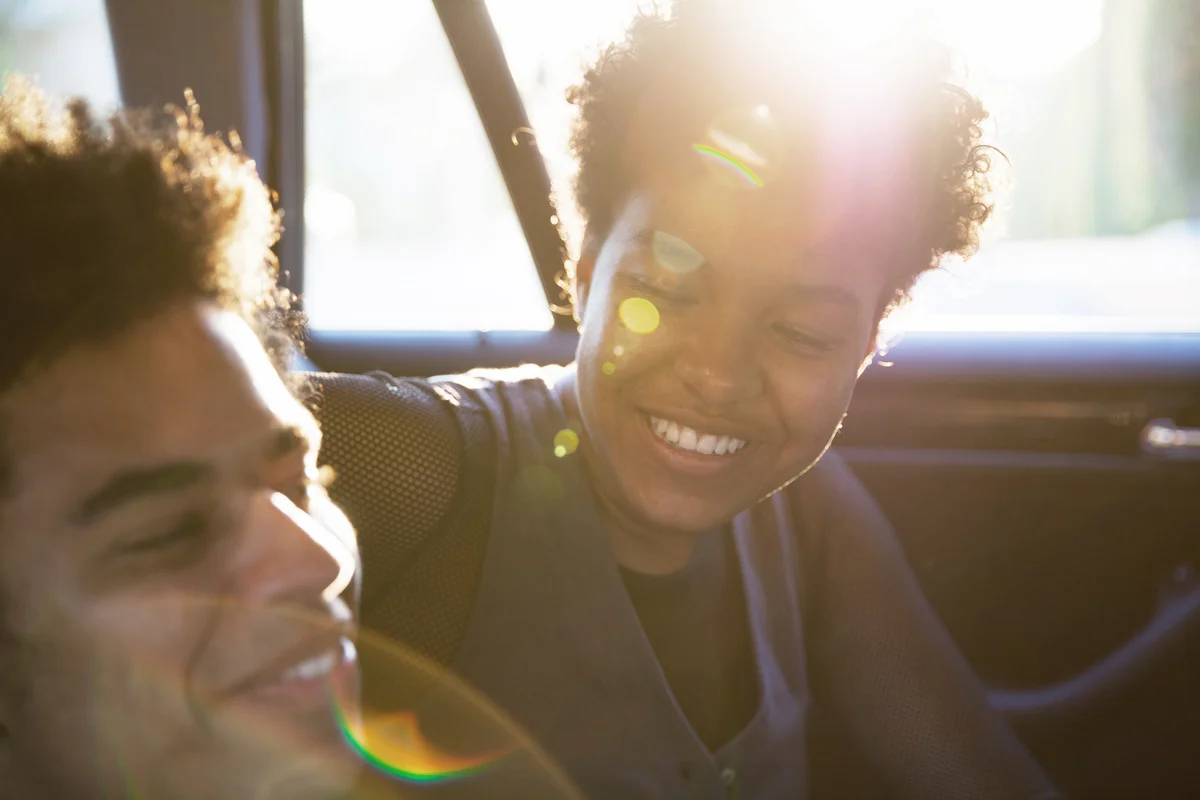 Happy young couple smiling and laughing in the back seat of a car