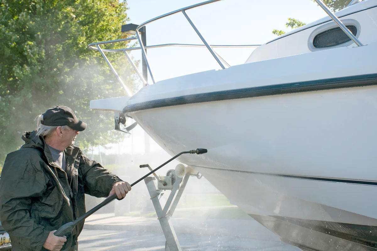 Man using pressure washer to clean boat hull