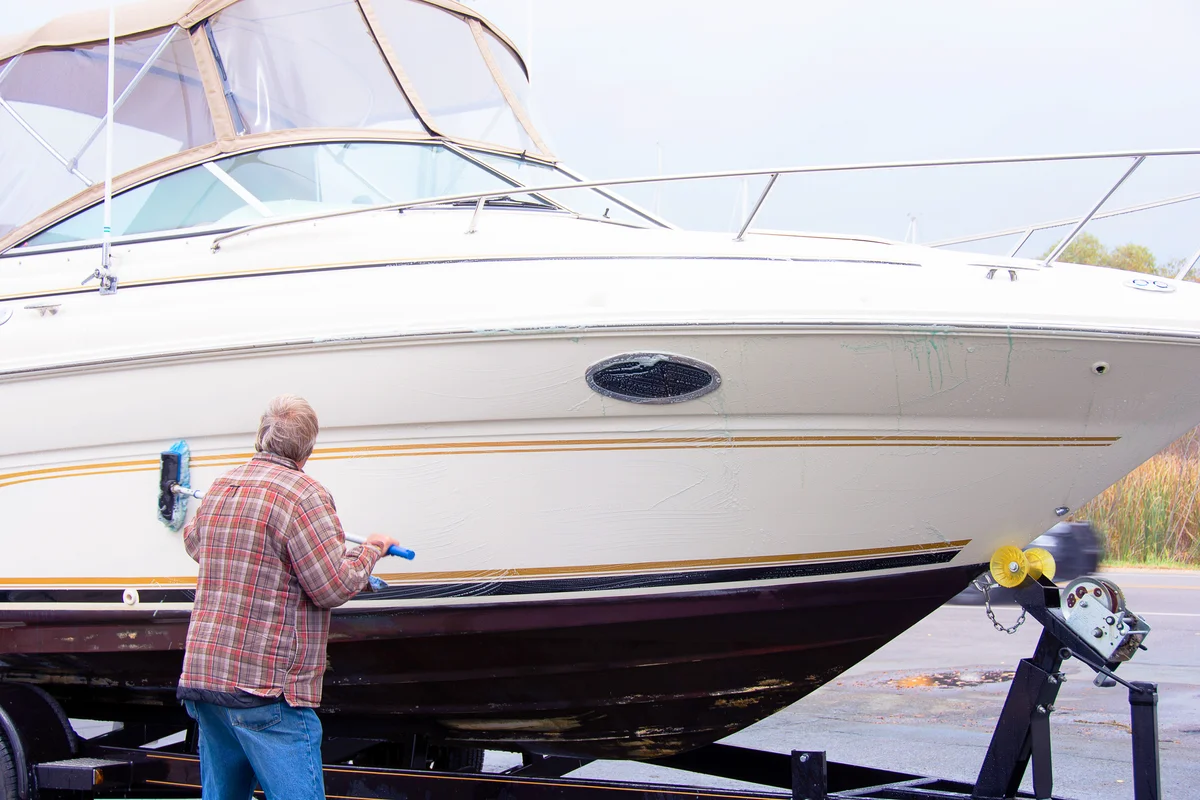 Man washing boat hull with long handle brush
