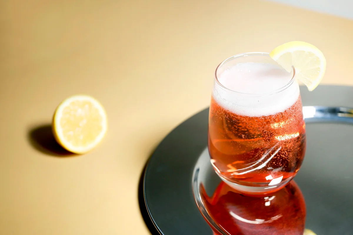 Pink fruit spritzer with bubbles, and a lemon wedge
