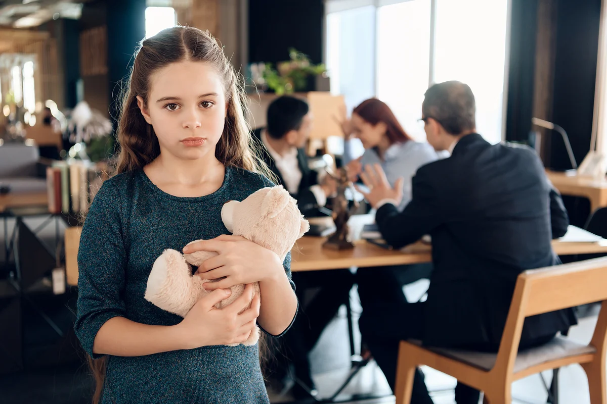 Sad girl stands with a bear in an advocate office