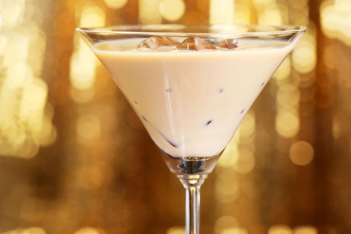 pumpkin spice cocktail in martini glass on golden background