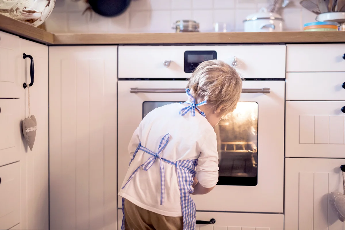 Rear view of small boy looking in the oven
