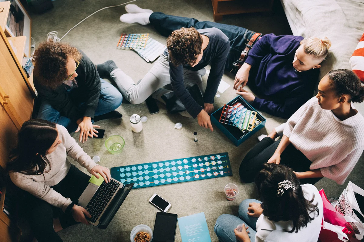Teenage girls and boys playing board game in bedroom