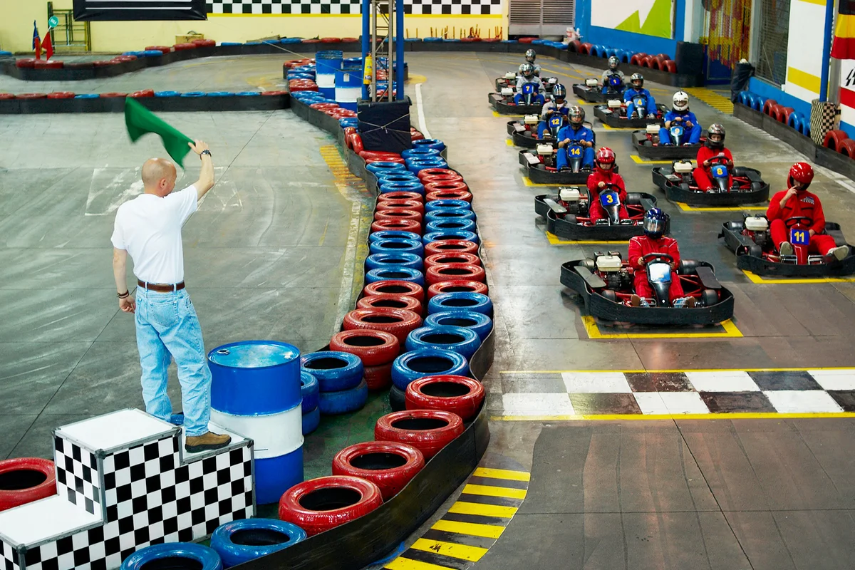 Go-cart racer at starting line with a man waving a flag