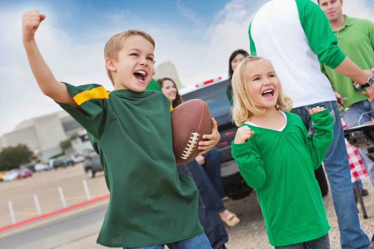 Excited kids tailgating with other fans at college football stadium