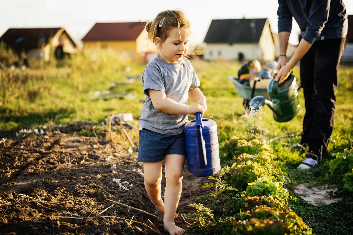 young girl watering plants in garden