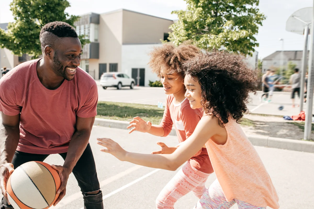 father playing basketball with his two daughters