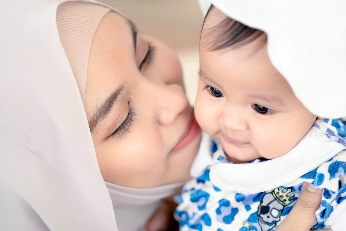 Muslim mother woman kissing and hugging a baby in her arms