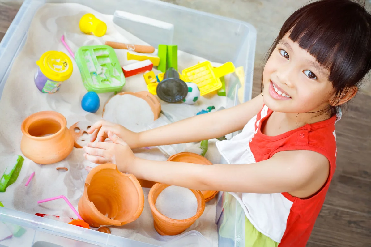 toddler girl playing with sensory bin objects