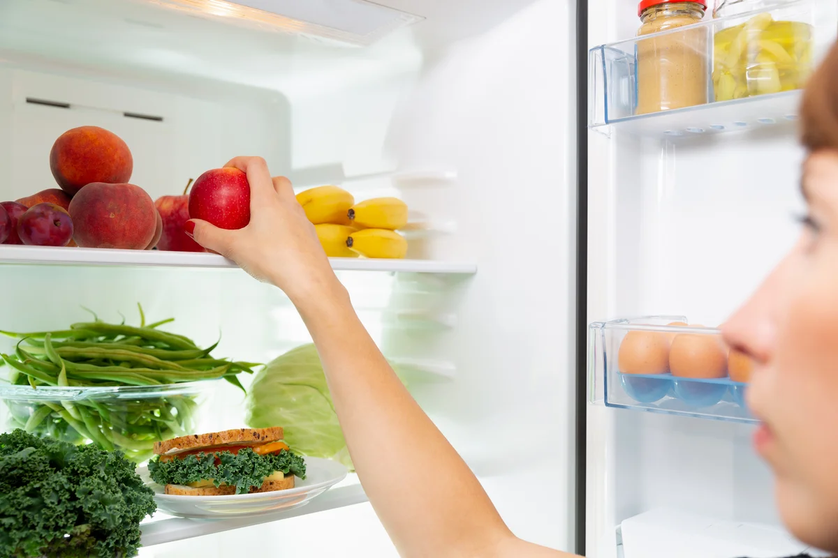 woman putting fruit in refrigerator