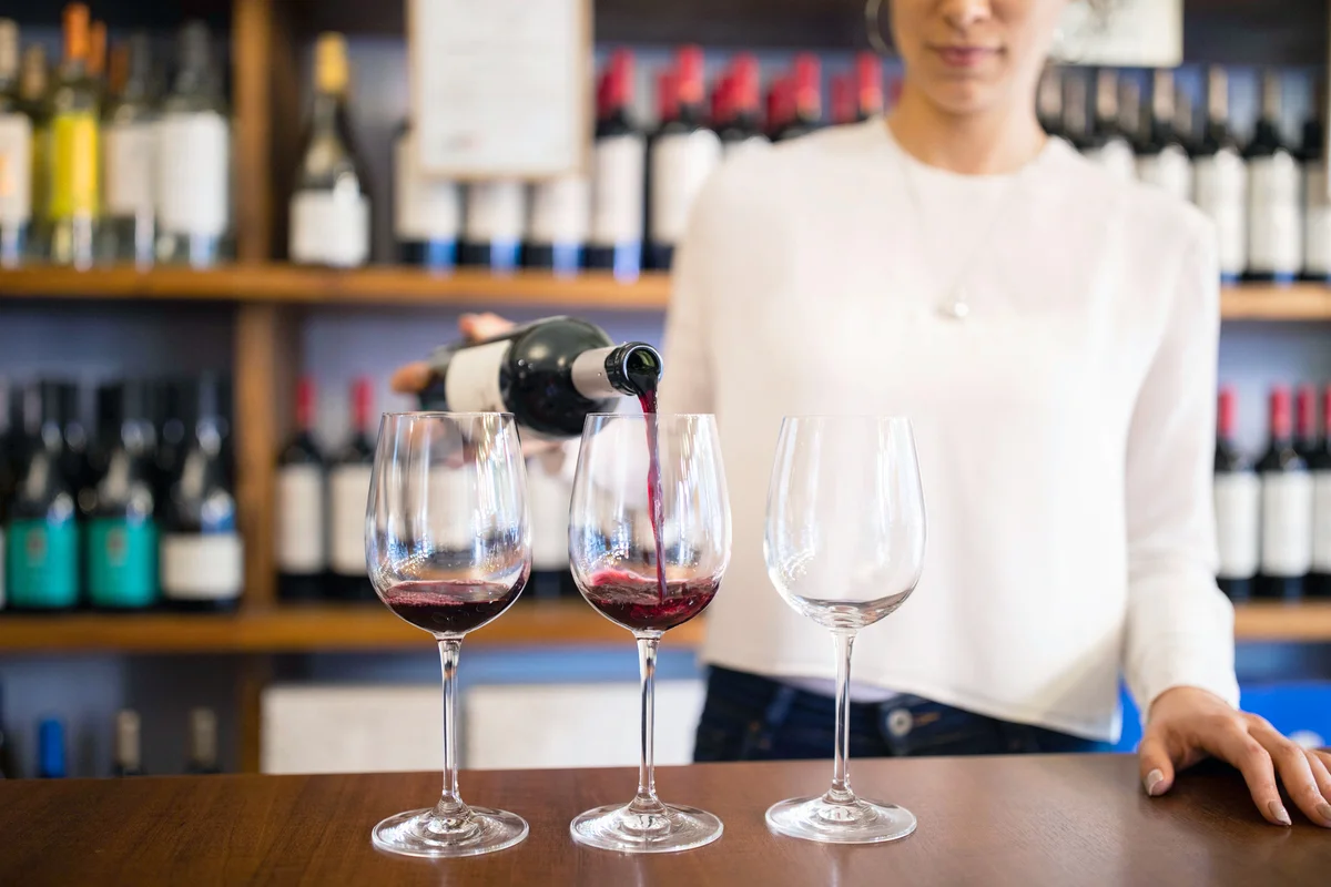 Bartender serving red wine in a winery