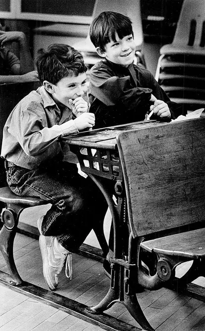 Kids sitting in 1900's school desk