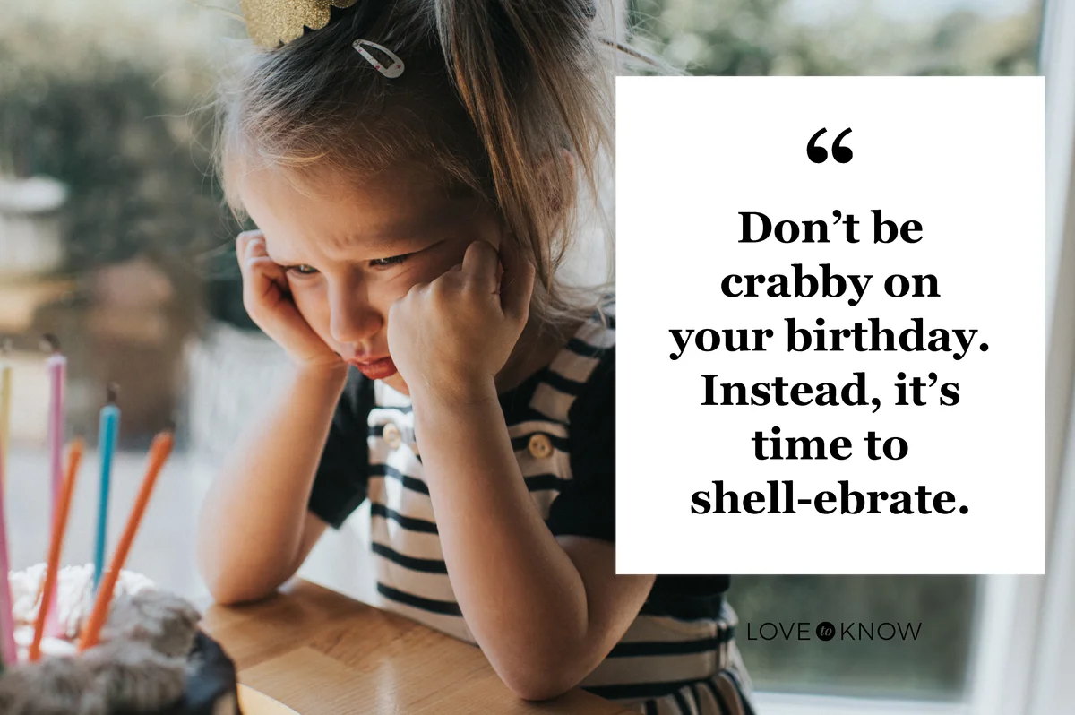 Young girl wearing a party hat, sulking in front of a birthday cake