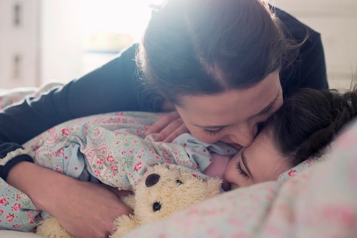 Affectionate mother with daughter in bed