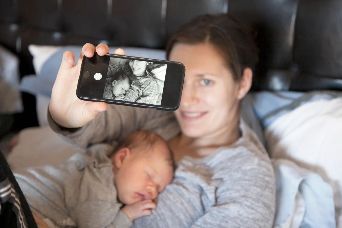 Baby girl sleeping on mothers chest, while mother takes selfie