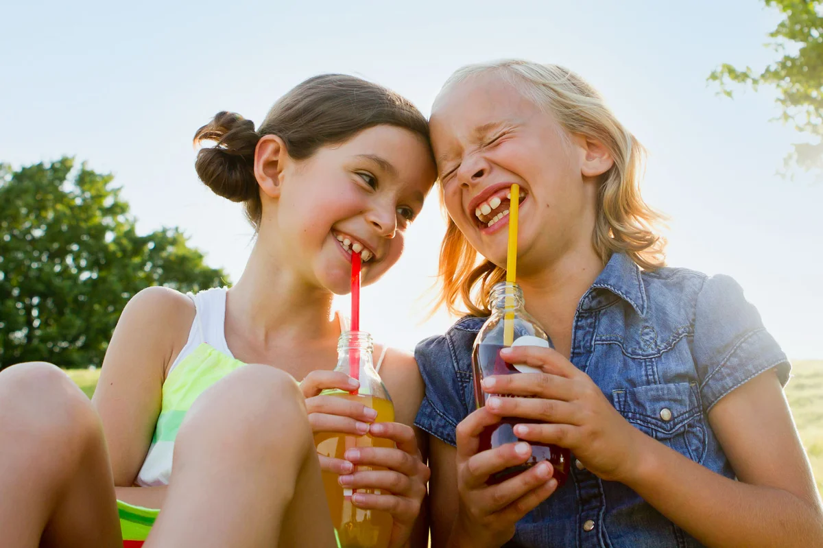 two girls drinking soda and laughing