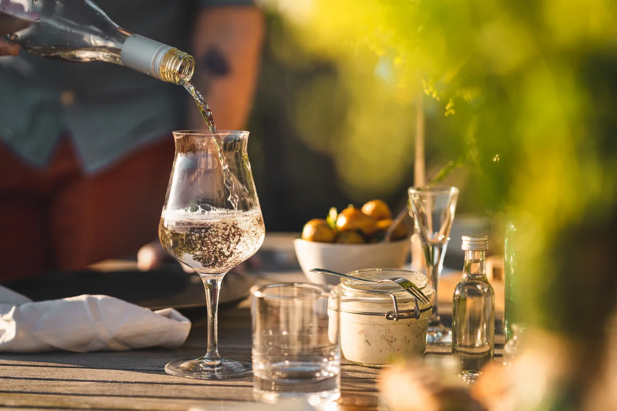 Man pouring up white wine at midsummer dinner