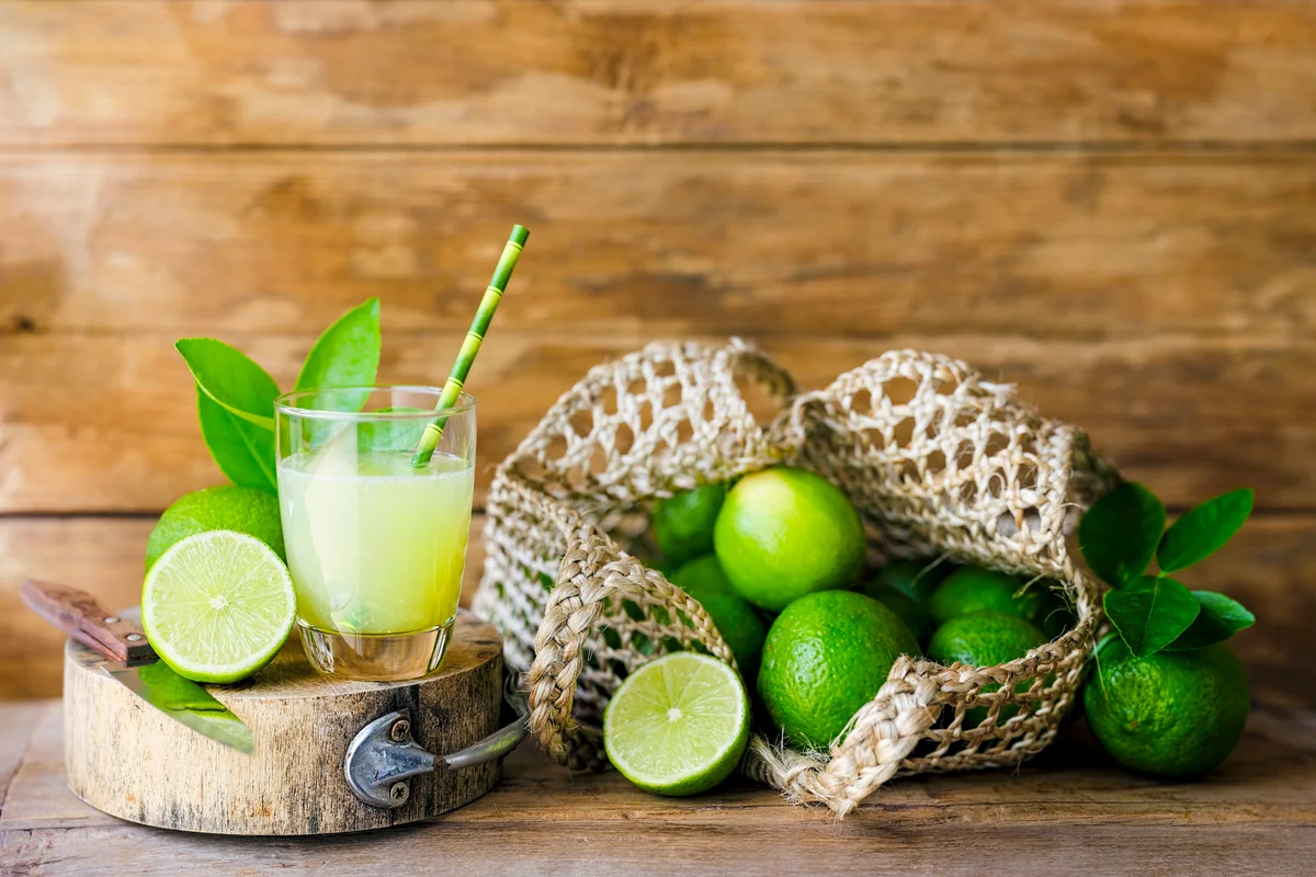 Limes next to a drinking glass with lime juice