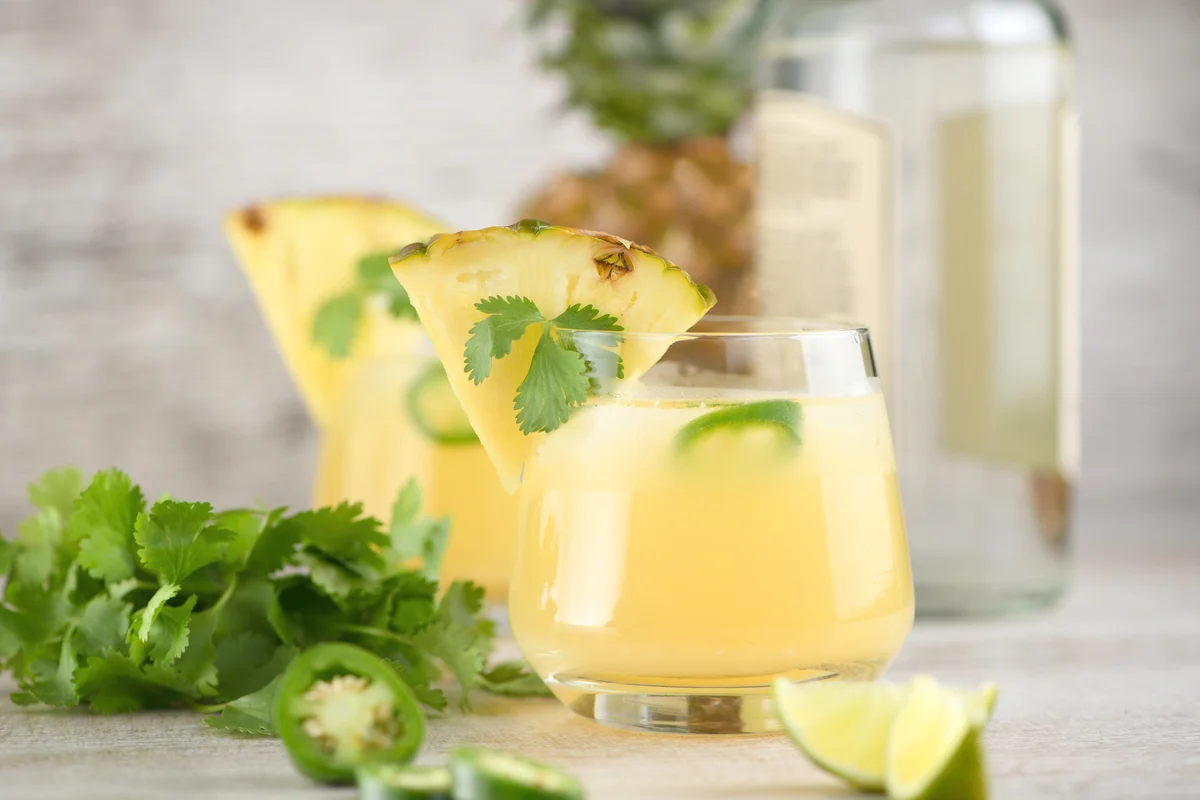 Tequila cocktail with pineapple juice, jalapeño slices and cilantro, cooled with ice