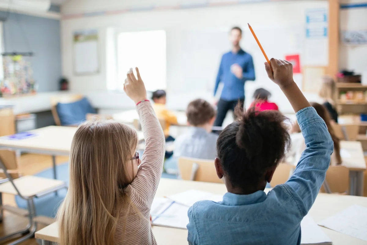 Students sitting with hands raised in classroom
